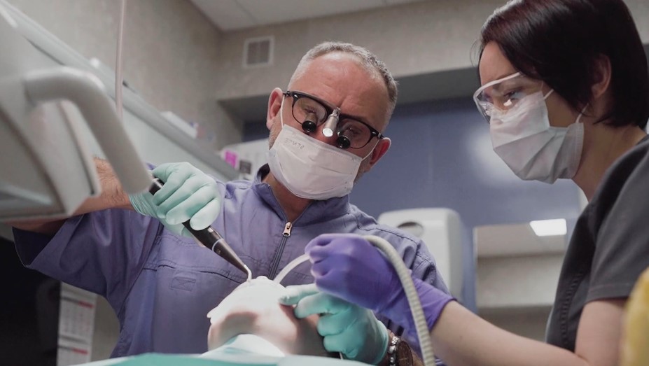 Dentist performing root canal with a dental assistant