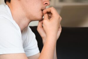 man chewing at his finger nails