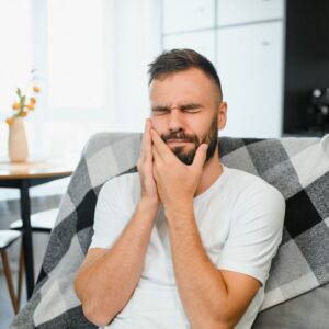 Emergency and Urgent Dental Pain - Man holding jaw with painful look